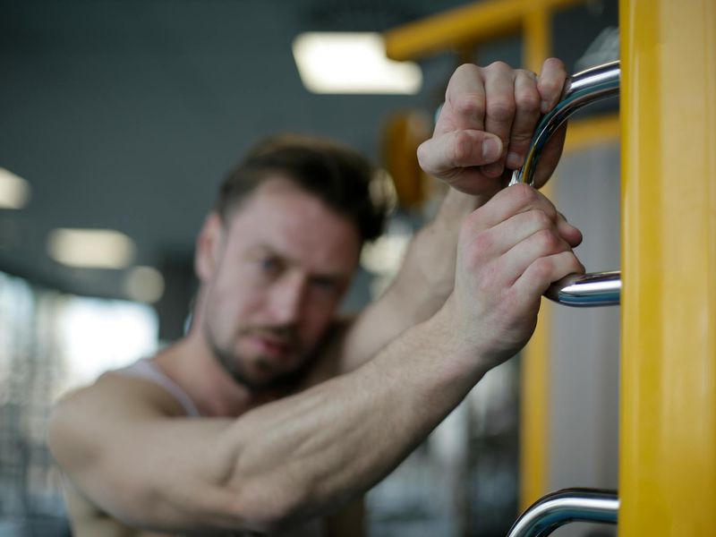 Close-up of gym equipment and a man preparing for session.
